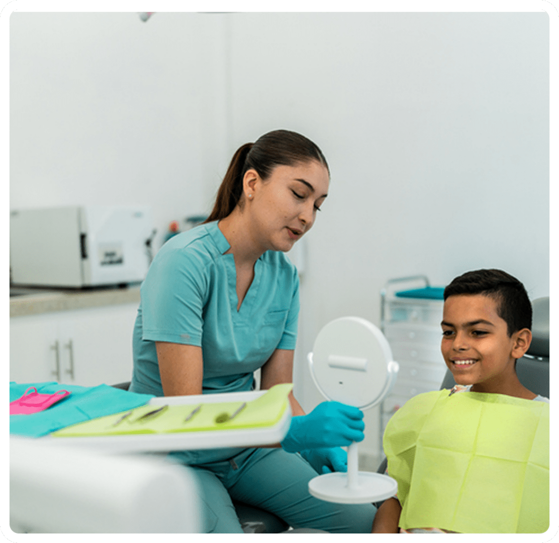 Dentist showing boy teeth in mirror.